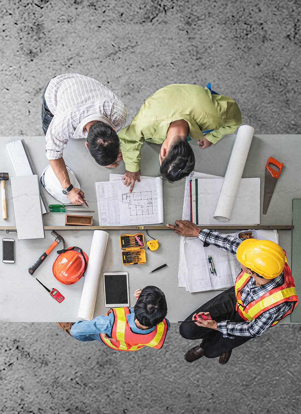 Group engineer and architects meeting at construction site,discussing, designing, planning, measuring layout of building blueprints in construction site floor at factory, top view and copy space