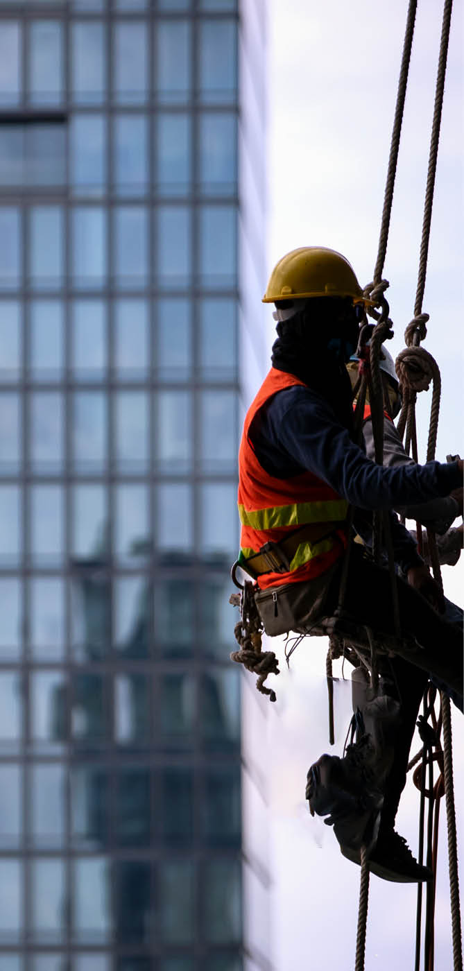 Construction worker wearing safety harness and safety line working at high place