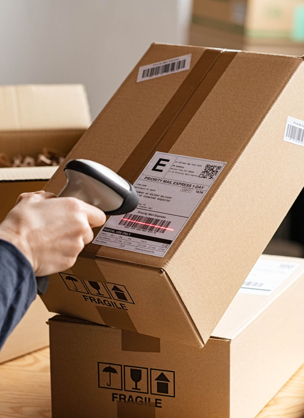 Hands of young woman scanning barcode on delivery parcel. Worker scan barcode of cardboard packages before delivery at storage. Woman working in factory warehouse reading and scanning labels on the boxes with bluetooth barcode scanner.